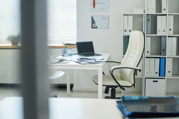 Part of medical office of physician or other specialist with workplace consisting of white leather armchair and desk with supplies