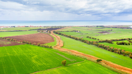 Fototapeta na wymiar Aerial view of cultivated and green fields. In the background the sea.