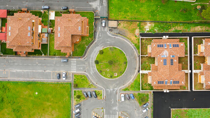 Aerial view on a roundabout road junction. Inside the rotunda a flowerbed with grass.
