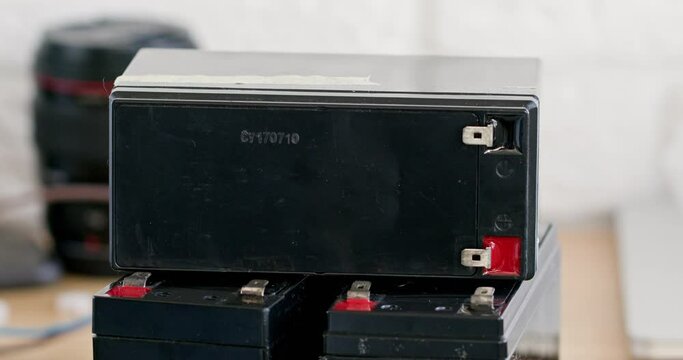 Male hand puts accumulator on batteries in workshop closeup. Charging equipment in store. Rechargeable device for harnessing electrical energy