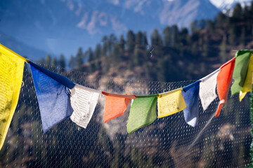 sacred religious multicolored prayer flags on fence moving in the wind showing a bhuddist prayer...