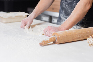 Dough for pizza, the chef rolls out the blanks. Closeup hand of chef baker in uniform white apron cook pizza at kitchen