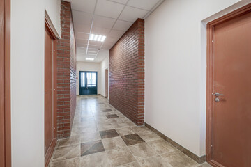 white empty long corridor with red brick walls in interior of modern apartments, office or clinic