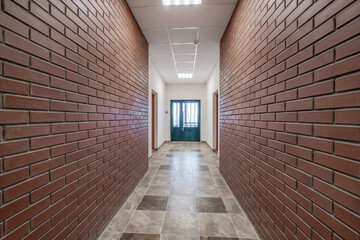 white empty long corridor with red brick walls in interior of modern apartments, office or clinic