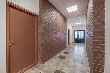 Fototapeta premium white empty long corridor with red brick walls in interior of modern apartments, office or clinic