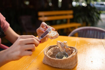 Caucasian woman hands eating bread garnishing with butter knife at restaurant table