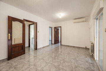 empty living room with gray stoneware floors, dark wood access doors with glass and access to a terrace with glass doors