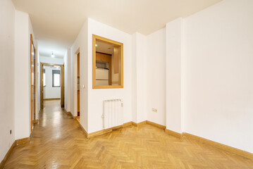 Living room of an empty apartment with a hatch window with an oak frame and parquet floors of the same material