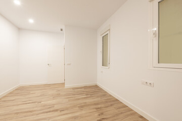 Empty loft apartment with white moldings on doors and skirting boards, aluminum windows, smooth white walls and light wooden floors, white aluminum radiators