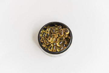 A round mother-of-pearl box with a black interior filled with pearls of a supreme liquid dietetic