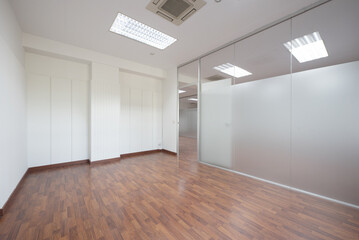 Empty office with technical ceilings, white walls with friezes and tempered glass separating wall with transparent door