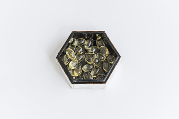 A hexagonal mother-of-pearl box with a black interior filled with pearls of a supreme liquid diet...