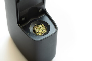 Cannabis, marijuana in an electric vaporizer, open vape closeup, hemp prepared in an inhalation device. THC, CBD, drugs and medicine concept, nobody, object macro, extreme closeup, modern vaporiser