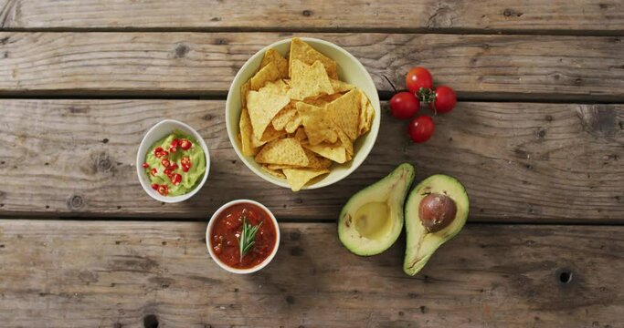Video of tortilla chips, guacamole and salsa dip on a wooden surface
