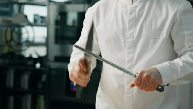 A chef sharpens a knife in a professional kitchen
