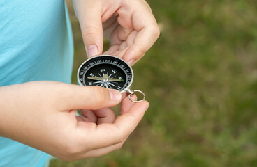 Anonymous elementary school age child holding a compass in hands, closeup, world directions, travel, journey, exploration symbol abstract concept, object up close, detail. Navigation, pathfinding © Tomasz