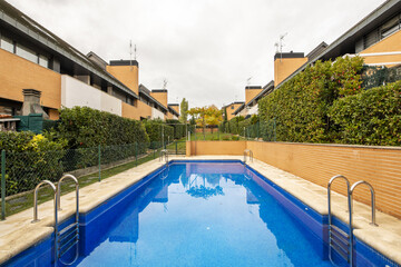 Community summer pool in the middle of a corridor between walled single-family homes