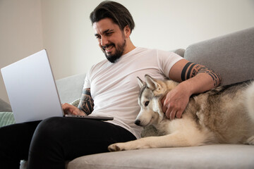 Handsome young man working on laptop homeoffice with his Husky dog