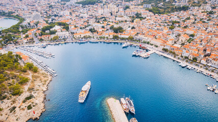 Croatia's harbor is a sight to behold from above. This breathtaking aerial view captures the colorful landscape filled with sailboats, motorboats, and luxurious yachts resting in a clear blue bay. Add - obrazy, fototapety, plakaty