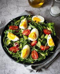Salad with egg, arugula, tomatoes. On a concrete background. Vegetarian