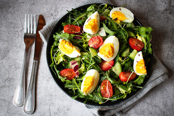 Salad with egg, arugula, tomatoes. On a concrete background. Vegetarian