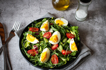 Salad with egg, arugula, tomatoes. On a concrete background. Vegetarian