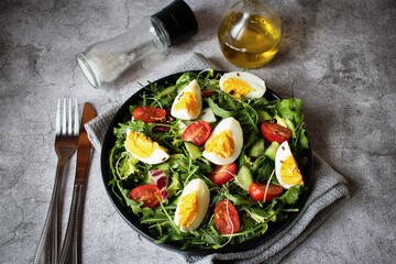 Salad with egg, arugula, tomatoes. On a concrete background. Vegetarian