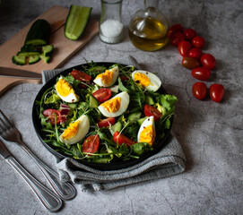 Salad with egg, arugula, tomatoes. On a concrete background. Vegetarian