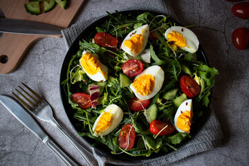 Salad with egg, arugula, tomatoes. On a concrete background. Vegetarian