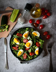 Salad with egg, arugula, tomatoes. On a concrete background. Vegetarian