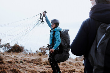 The man extends the jump ropes on a paraglider. A man secures his equipment to jump with a tourist 