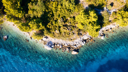 A drone captured the stunning aerial view of Croatia's coastal area, which features crystal-clear blue water and lush forests on land.