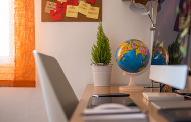 Desk Table Of A Student At Home With Office Supplies And Laptop. Focus On The Globe