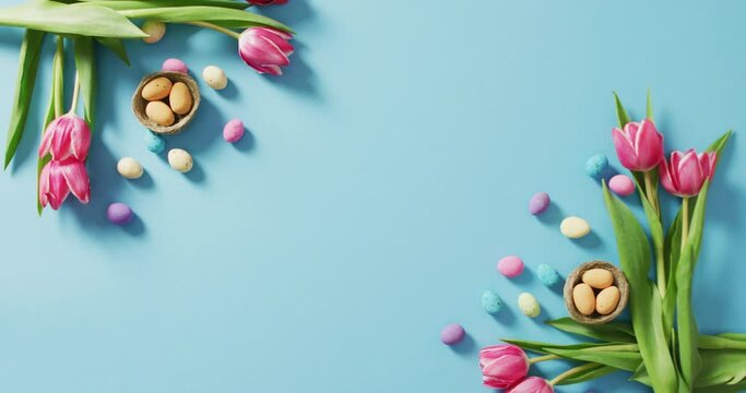 Video of decorated colorful easter eggs and flowers on a blue surface