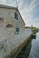 Fototapeta na wymiar Facade of a beautiful stone building on the edge of a river in Galicia, Spain