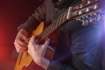 The guy in the dark shirt is plucking the strings of a six-string guitar