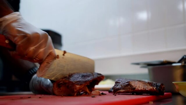 black chef cutting roasted chicken on kitchen table, professional cook in restaurant, use cleaver