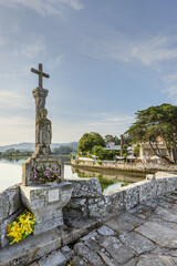 Fototapeta premium View on the Romanesque bridge of the Miñor river in La Ramallosa that connects Baiona with Nigran in Galicia, Spain a beautiful summer morning with calm water next to a cruise ship with fresh flowers