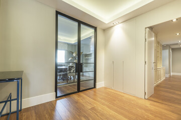 distributor of a house with access to several rooms with built-in wardrobes, custom-made wooden bookcases and black metal and glass doors