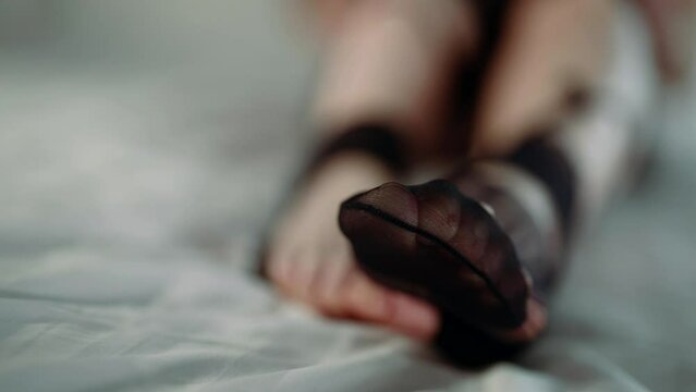 woman in torn black nylon tights in bed, closeup view of feet, victim of rape, domestic violence