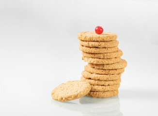 Fototapeta na wymiar Stack of oatmeal cookies with cranberries on top on light glass background
