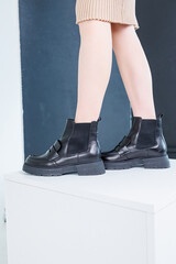 Close-up of female legs in black leather chelsea boots. Women's comfortable spring casual shoes. Black women's spring chelsea boots