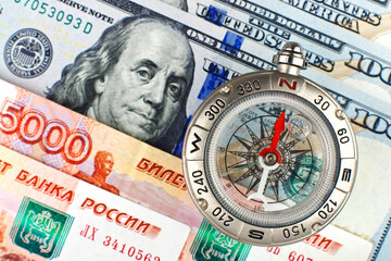 Compass with arrow pointing up on the background of Russian and American banknotes