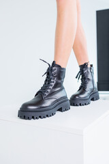 Close-up of female legs in black leather lace-up boots. Women's comfortable spring casual shoes. Black women's spring boots