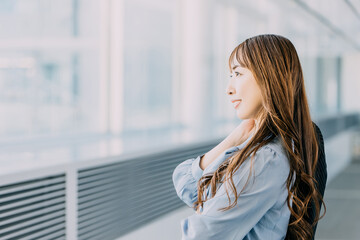 Fototapeta premium 窓の外を眺める笑顔のビジネスウーマン 日本人女性