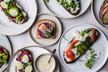 Mix of homemade smorrebrods (open sandwiches) with different toppings: avocado-salmon-cream cheese, herring-beetroot paste, green peas-cottage cheese, quail eggs -beetroot-cream cheese.