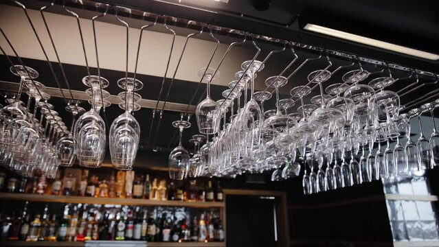 Lots of clean empty wine glasses hanging on a rack in some restaurant. Washed glasses to a glassware holder in a bar counter
