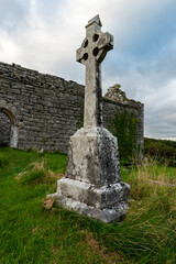 Fototapeta na wymiar Huge Celtic cross gravestone standing in front of the ruins of Carran Church, The Burren National Park, County Clare, Ireland