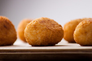 Classic Spanish croquettes on wooden board with dim light in the background	
