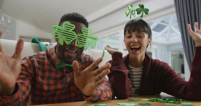 Portrait of happy diverse couple wearing clover shape items and having video call